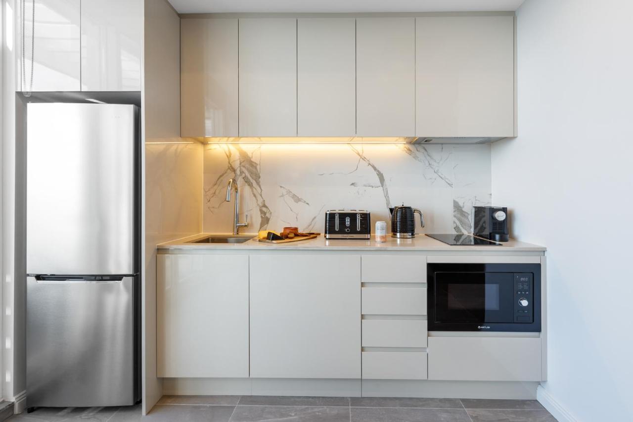 Meriton Suites Bondi Junction Sydney Bagian luar foto The photo shows a modern kitchen featuring a sleek design. It includes light-colored cabinetry with a smooth finish and upper cabinets that blend seamlessly with the wall. The countertop is made of a light stone, complementing the overall aesthetic. 